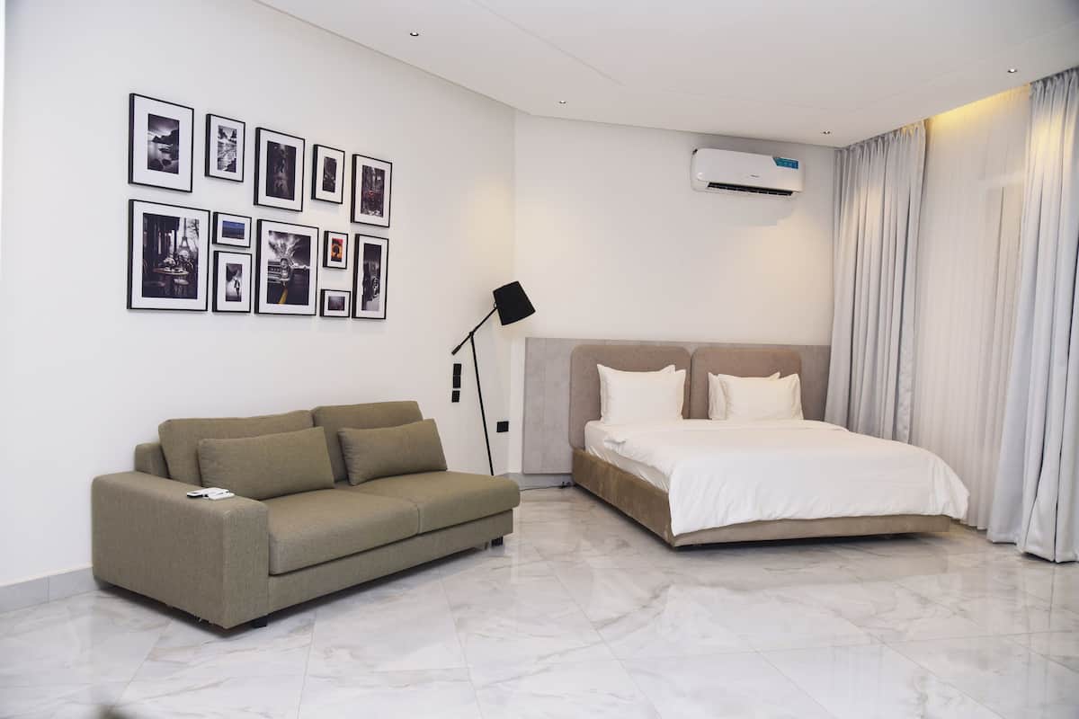 Ein modernes Hotelzimmer mit Bett, einer Couch, einer Wandklimaanlage und mehreren gerahmten Bildern.