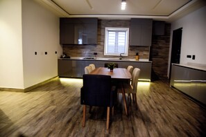 Eine moderne Küche mit Essbereich, Holzboden, dunklen Schränken und einem Fenster, das für natürliches Licht sorgt.