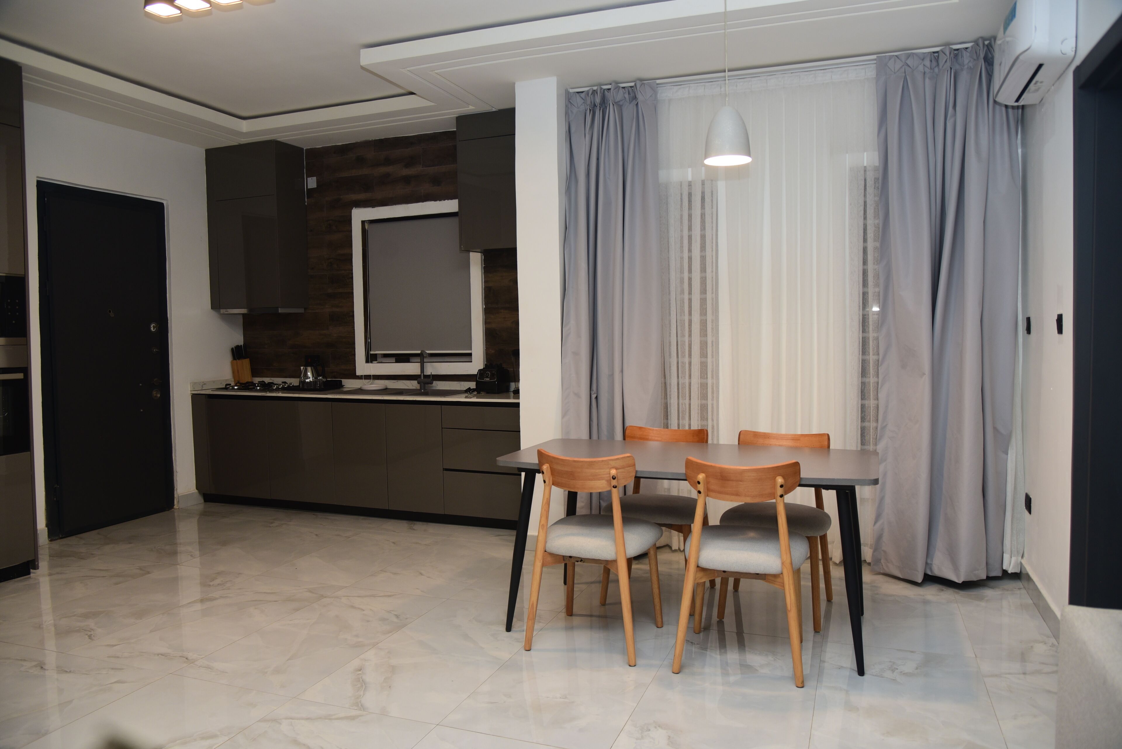 Una cocina moderna con armarios oscuros, encimera de madera y horno empotrado.