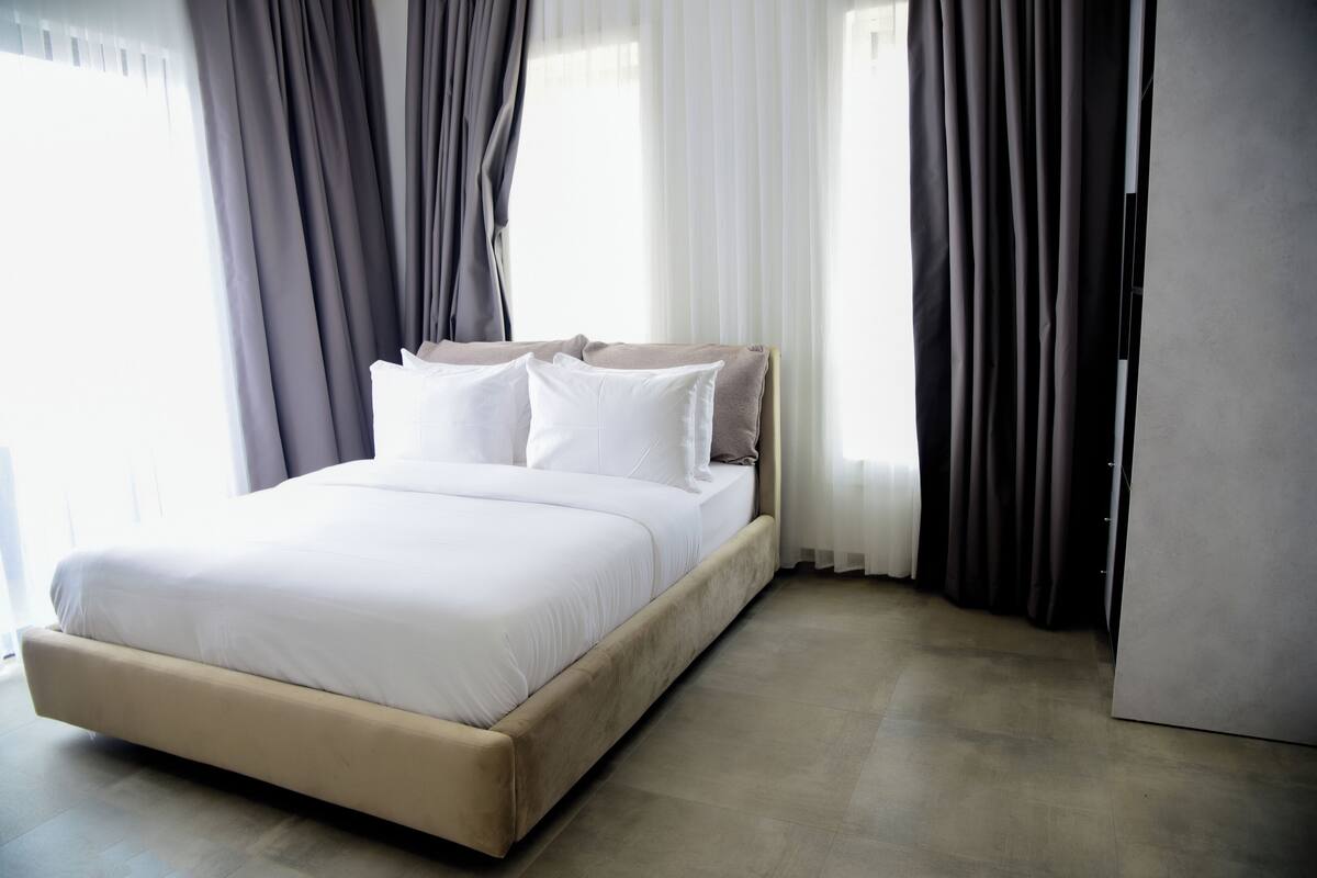 Ein ordentlich bezogenes Bett mit weißen Leinen in einem modernen Hotelzimmer.