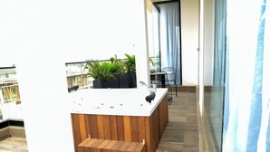A modern kitchen with a wooden countertop and built-in appliances, a small seating area with a bench, and a balcony with plants. - Hotel De Alommah Kubwa Abuja Nigeria (Abuja)