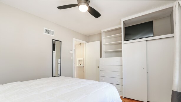 A bedroom with a bed, a wardrobe, a television, and a ceiling fan. - Charming 3-bedroom house in quiet neighborhood (Wichita)