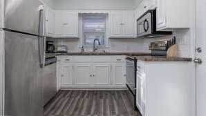 A modern kitchen with white cabinets, stainless steel appliances, and a granite countertop. - Charming 3-bedroom house in quiet neighborhood (Wichita)