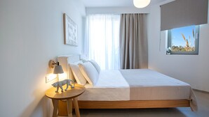Une chambre d’hôtel moderne, équipée d’un lit, d’une table de chevet avec une lampe, d’un tableau encadré au mur et d’une fenêtre donnant sur l’extérieur.