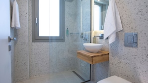 Une salle de bain moderne avec une baignoire sur pieds, un grand miroir et une fenêtre laissant entrer la lumière naturelle.