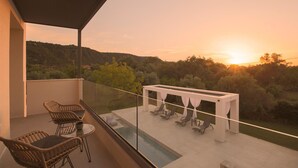 Uma varanda com cadeiras de vime, uma mesa de vidro e uma piscina.