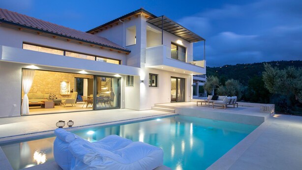 Une maison moderne à deux étages, dotée d’une piscine, d’un espace extérieur aménagé et d’un intérieur bien éclairé.