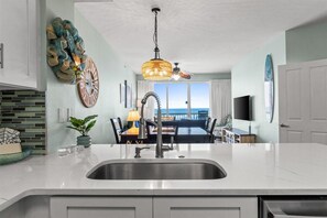 Una cocina moderna con un lavamanos de acero inoxidable, un comedor con vistas y un elemento decorativo en la pared.