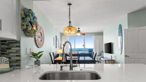 Una cocina moderna con una isla grande, pileta de acero inoxidable y un comedor con vistas.