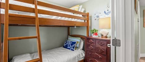Ein Stockbett mit Holzrahmen, eine Kommode mit mehreren Schubladen und eine Wanduhr.