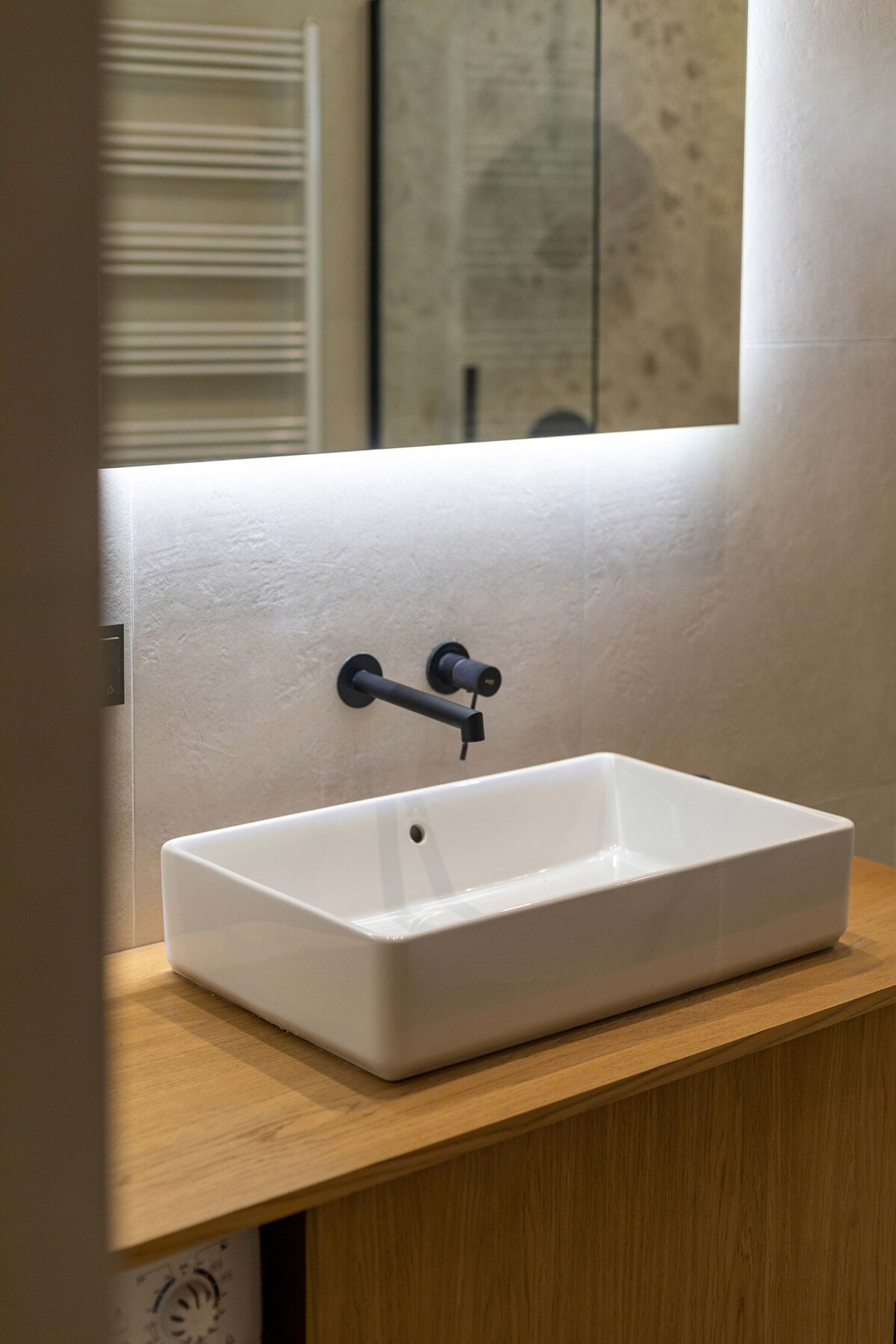 Un évier rectangulaire blanc, surmonté d’un robinet noir, est installé sur un plan de travail en bois.