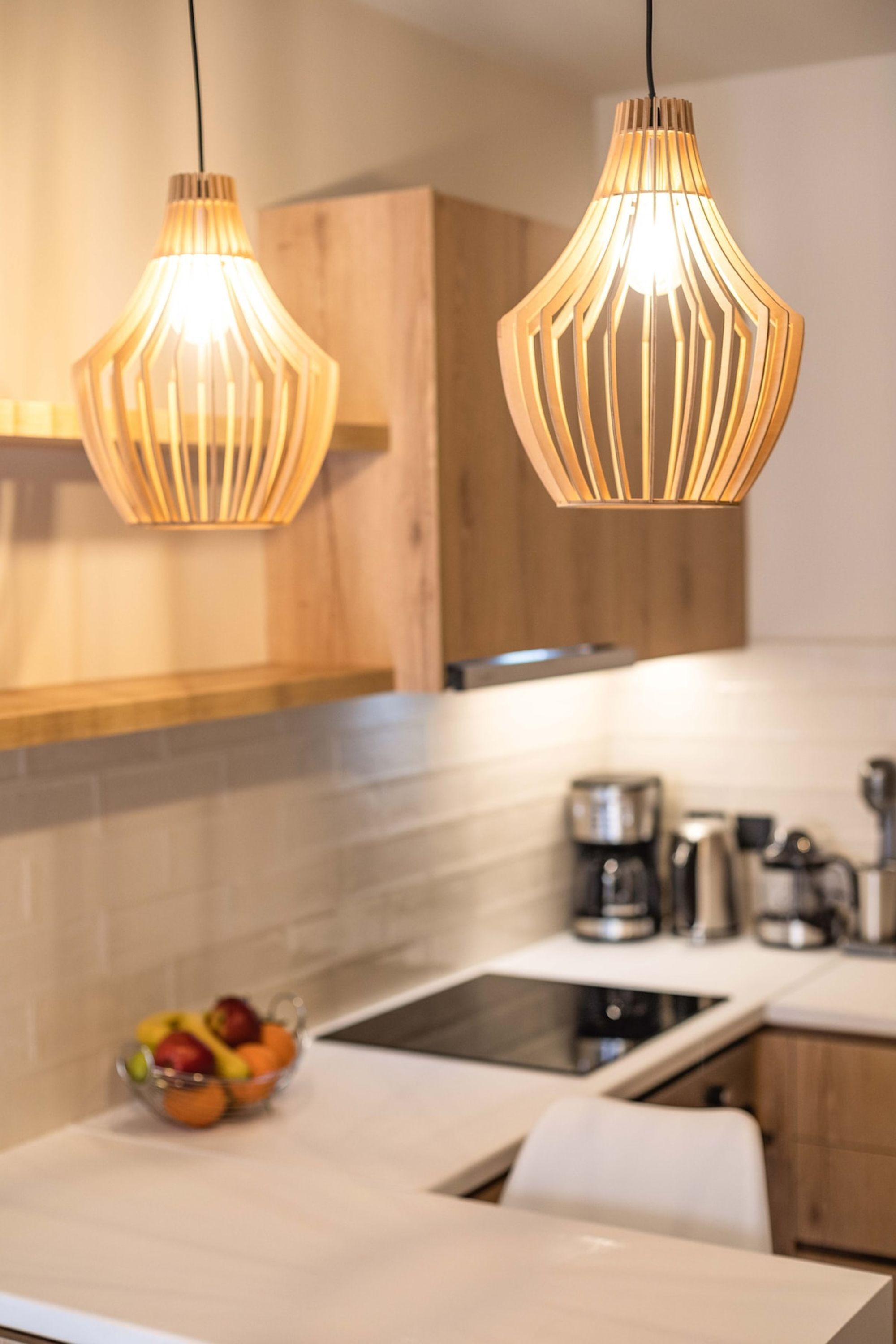 A modern kitchen with wooden cabinets, a white countertop, and two pendant lights.