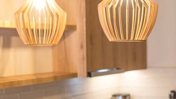 A modern kitchen with wooden cabinets, a white countertop, and two pendant lights.