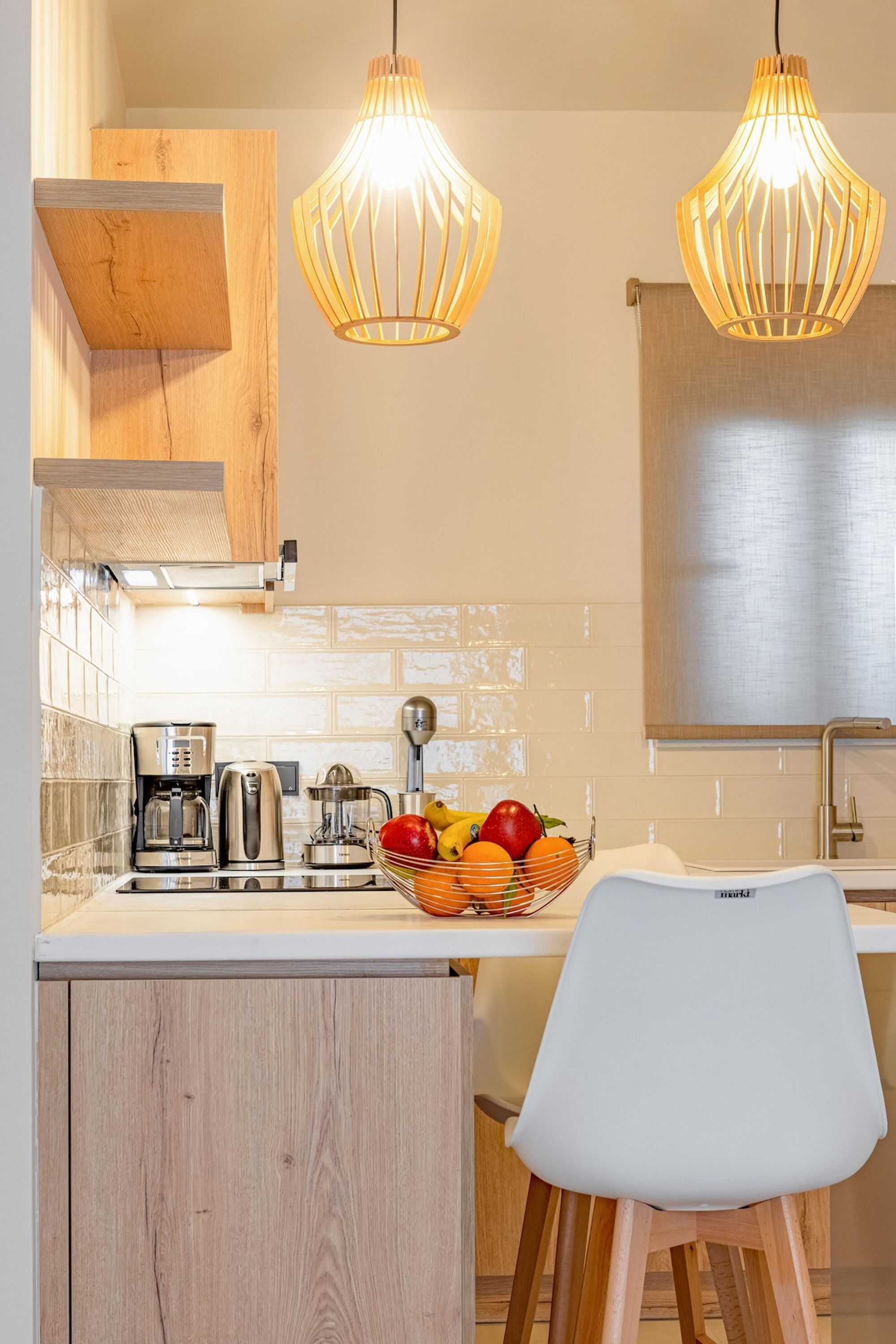 A modern kitchen with wooden cabinets, a white countertop, a sink, and two pendant lights.