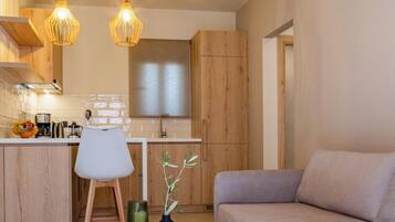 A modern kitchen with wooden cabinets, a dining area with a round table, and a sofa.