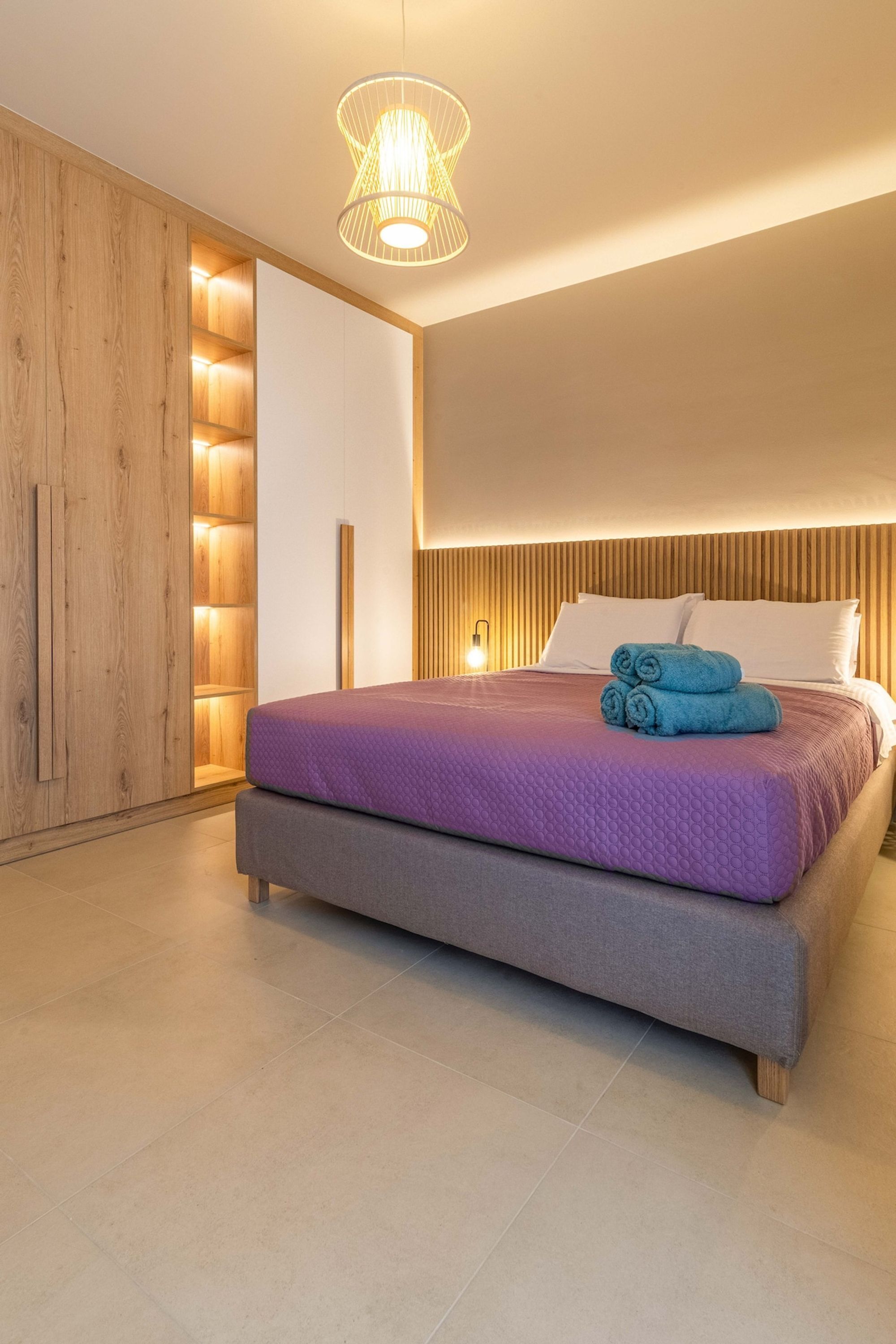 Un dormitorio moderno con una cama grande, paneles de madera y una lámpara de techo original.