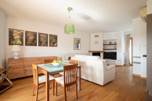 Una sala de estar con sofá, mesa de comedor, sillas, televisión y obras de arte en la pared.