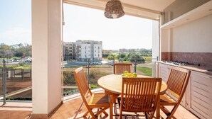 A balcony with a round wooden table and chairs, a hanging light fixture, and a view of buildings and a parking lot. - Gimber Lofts 2 by Klodge- vintage flat with Wi-Fi (Olbia)
