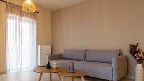Een moderne woonkamer met een grijze bank, twee houten salontafels en twee hanglampen.
