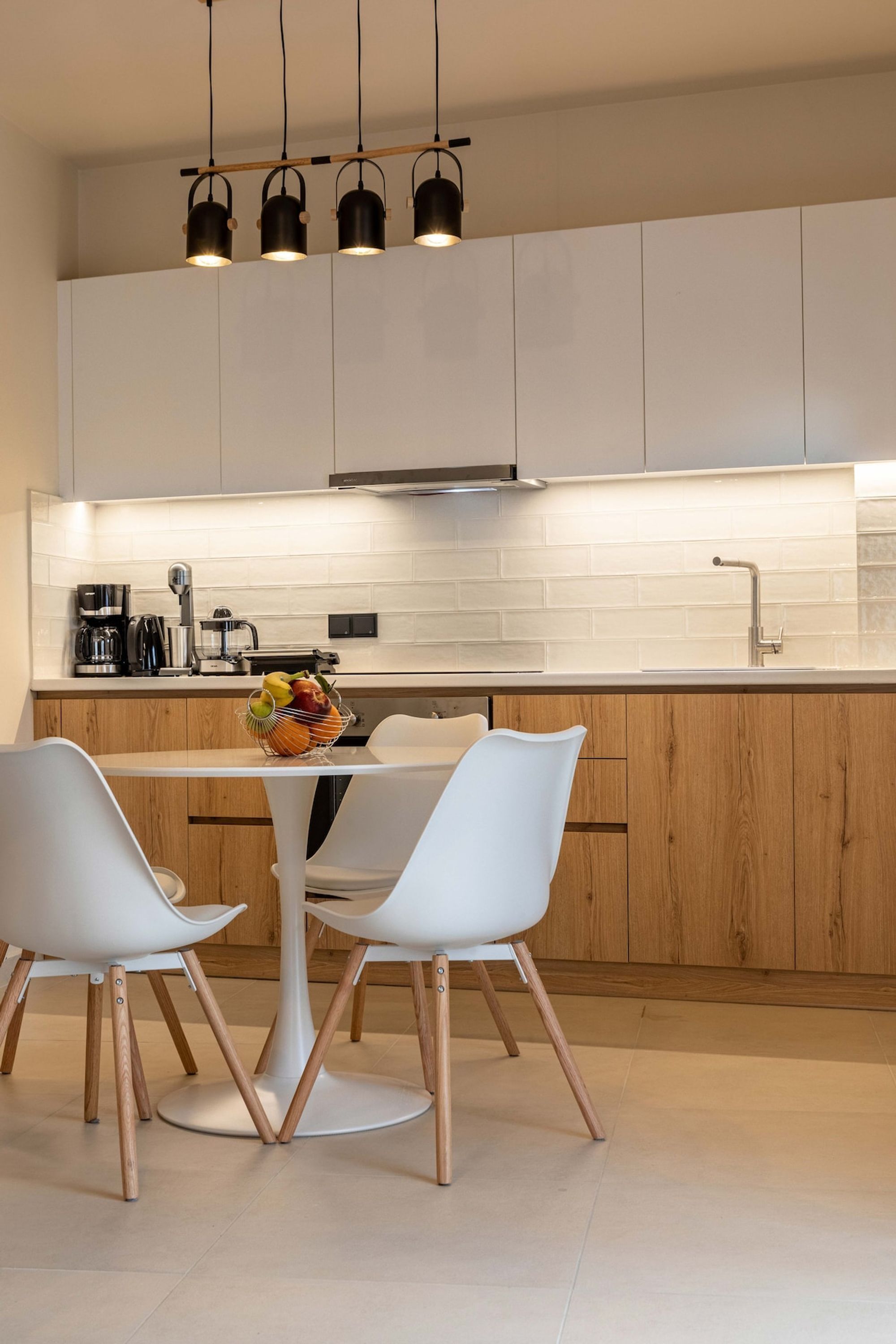 A modern kitchen with white cabinets, a wooden countertop, and a dining area with white chairs and a round table.