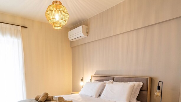 Een moderne slaapkamer met een houten bed, een nachtkastje, een hanglamp en een raam met gordijnen.