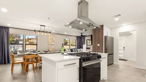 Een moderne keuken met een centraal eiland, een inbouwoven en roestvrijstalen apparatuur.