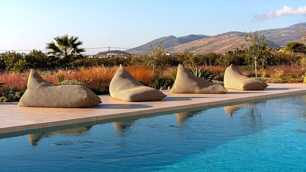 A poolside area with four woven bean bags and a clear view of mountains in the background. - Luxury Villa Jaspis Paros (Isterni)