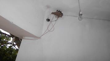 A ceiling with exposed wiring and a light bulb fixture.
