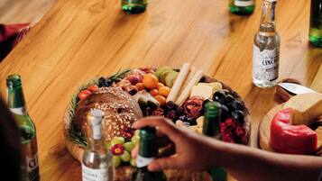A wooden table with a variety of food items and bottles, likely for a gathering or party.