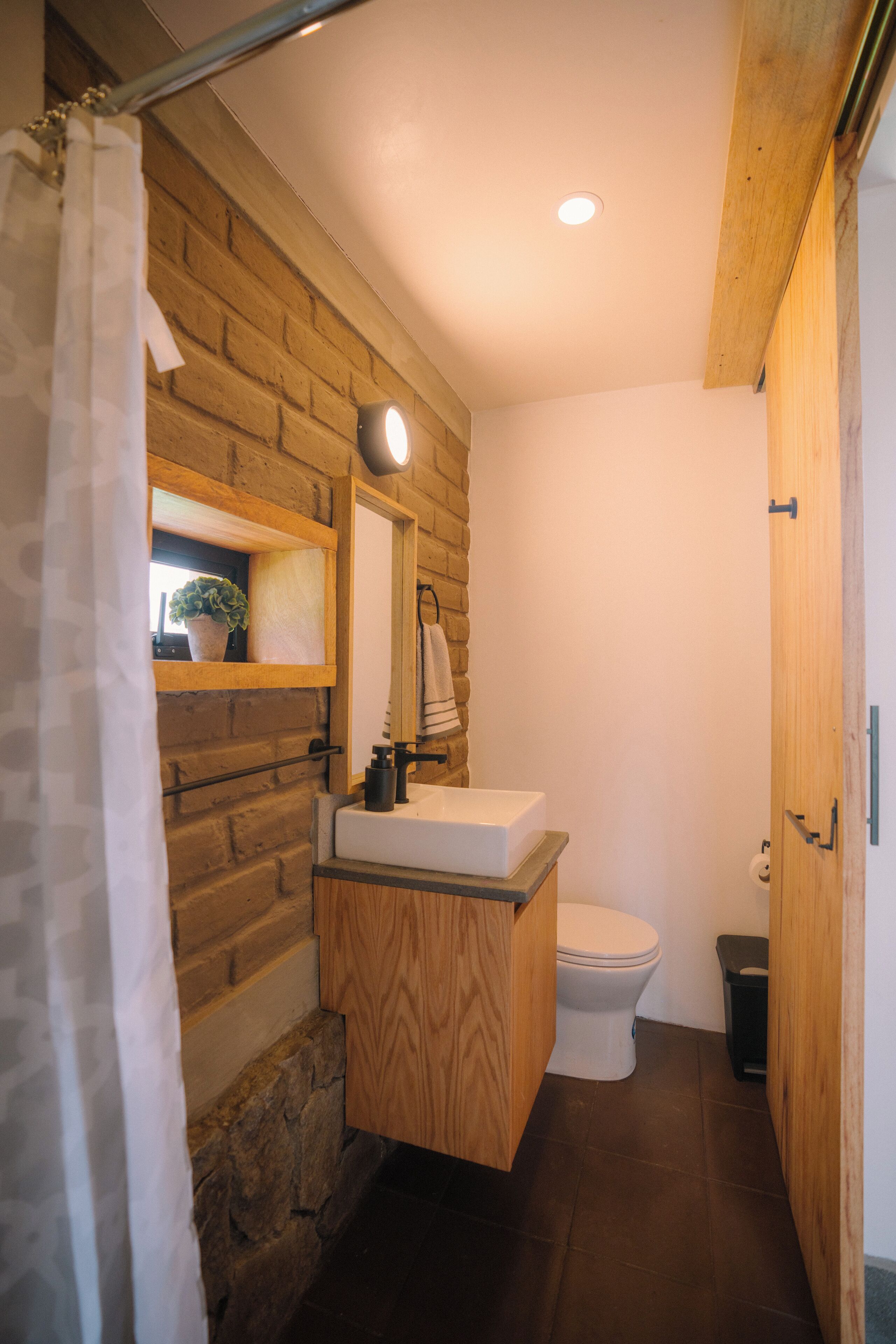 Une salle de bain avec un meuble-lavabo en bois, un lavabo blanc et des toilettes.