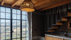 Una cocina moderna con una mesa y banco de madera, ventanas amplias y vistas al campo.