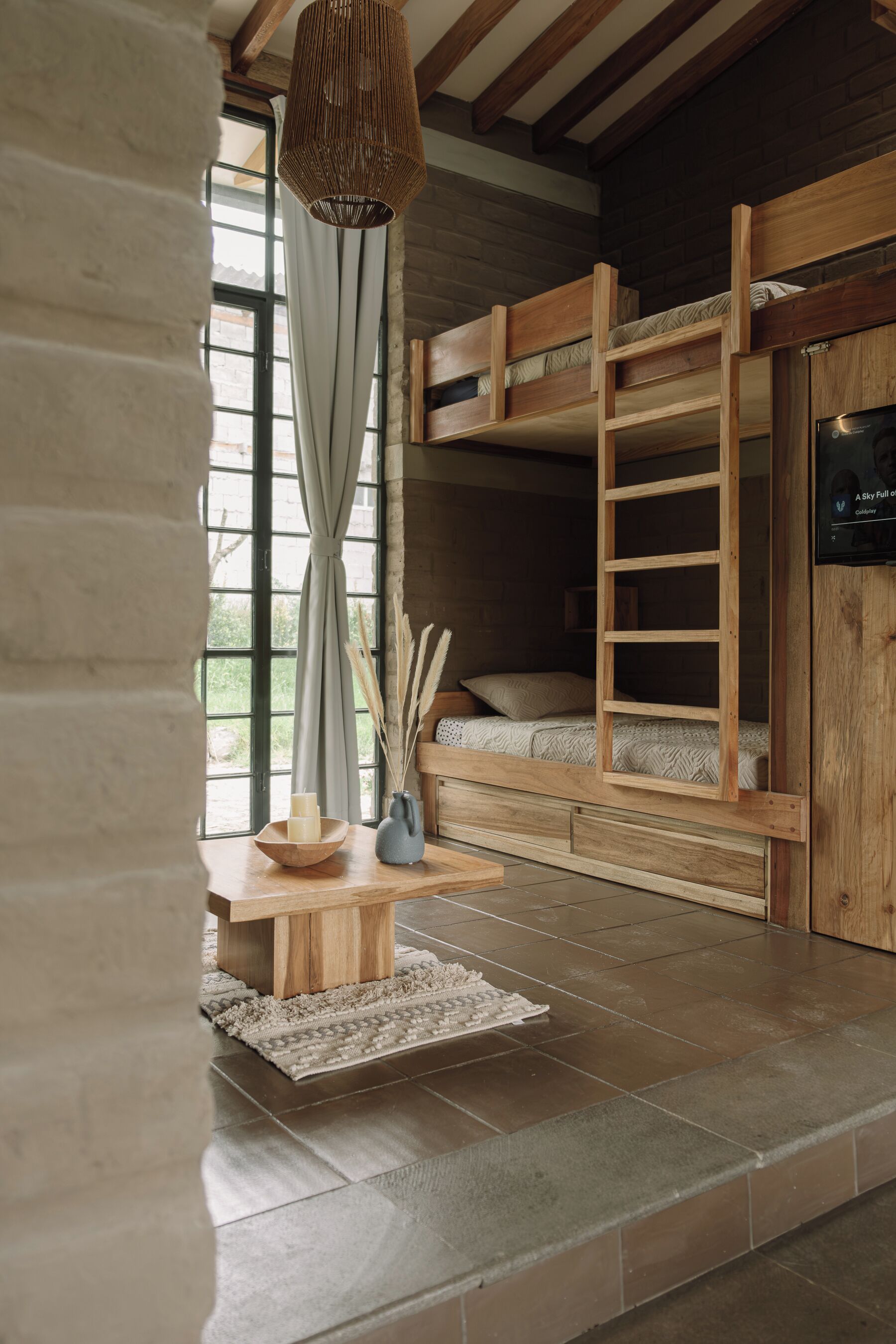 Una habitació acollidora amb un llit superposat, una taula de fusta amb espelmes i una finestra gran amb cortines.