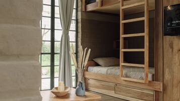 Una habitació acollidora amb un llit superposat, una taula de fusta amb espelmes i una finestra gran amb cortines.