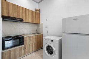 A modern kitchen with wooden cabinets, a built-in oven, a washing machine, and a refrigerator. - Sun & Beach Apartment in Chania 8 (Chania)