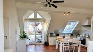 Eine moderne Küche mit Essbereich, Deckenventilator und Blick durch Glastüren.