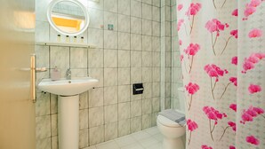 Kylpyhuone, jossa on valkoinen pesuallas, peili ja wc-istuin.