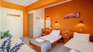 Hotellihuone, jossa on kaksi sänkyä, puinen pääty, yöpöytä lampun kanssa, peili ja pieni pöytä, jossa on kasvi.