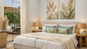 Un dormitorio con una cama grande, dos lámparas de pared y vistas a un patio con una silla y una sombrilla.