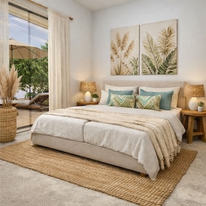Ein Schlafzimmer mit einem großen Bett, zwei Wandlampen und Blick auf eine Terrasse mit Stuhl und Sonnenschirm.
