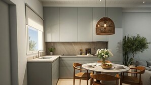 Una cocina moderna con gabinetes grises, una mesa redonda de comedor con sillas de madera, una lámpara colgante y una planta en maceta.