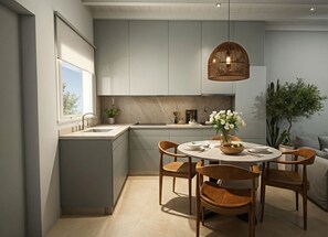 Eine moderne Küche mit grauen Schränken, einem runden Esstisch mit Holzstühlen, einer Pendelleuchte und einem Blumentopf.