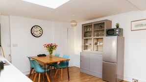 A compact kitchen with a dining table, teal chairs, a clock, and a microwave. - Historic Castle & Central Location To Arundel's Iconic High St (Arundel)