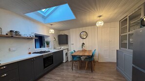 A modern kitchen with a skylight, wooden flooring, and a dining area with blue chairs. - Historic Castle & Central Location To Arundel's Iconic High St (Arundel)