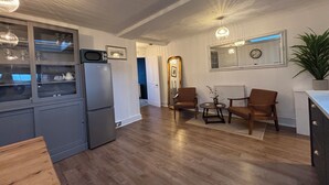 A modern kitchen with a built-in microwave and refrigerator, wooden flooring, and a skylight. There are two brown chairs and a small table with a potted plant. - Historic Castle & Central Location To Arundel's Iconic High St (Arundel)