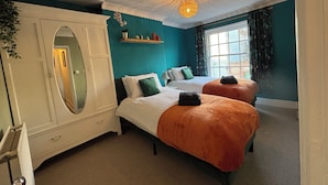 A bedroom with two beds, a white wardrobe, teal walls, and a window with curtains. - Historic Castle & Central Location To Arundel's Iconic High St (Arundel)
