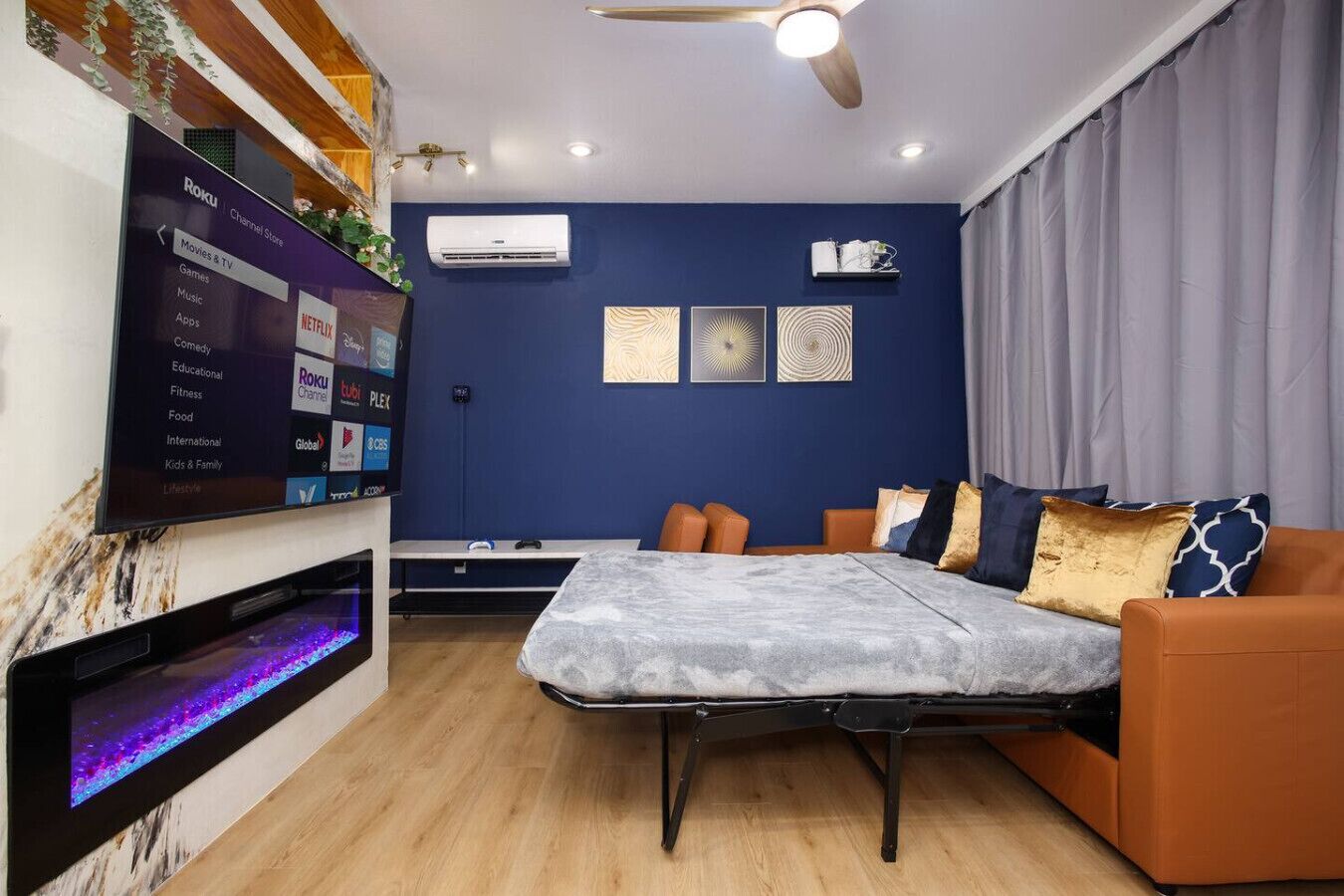 A modern bedroom with a bed, a TV, and a ceiling fan.