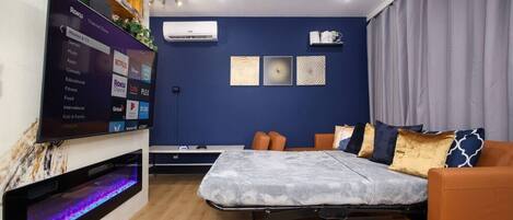 A modern bedroom with a bed, a TV, and a ceiling fan.
