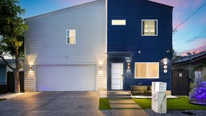 Een modern huis met twee verdiepingen, een garage, een verzorgd gazon en een oprit.