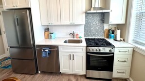 Eine Küche mit weißen Schränken, einem Edelstahlkühlschrank, einem Gasherd und einem Backofen.