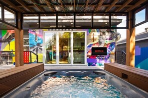 A hot tub area with a Netflix sign, colorful murals, and a wooden deck. - City Views Rooftop Karaoke, Pool, Hot Tub, Games (San Antonio)